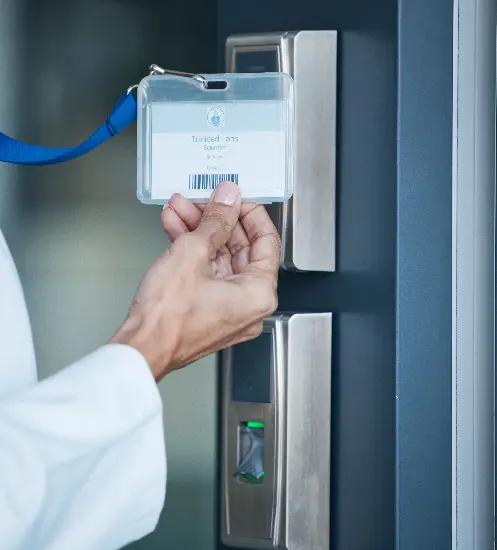 Persoon houdt een toegangsbadge voor een elektronische badgelezer naast een deur om toegang te krijgen.